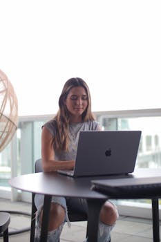 A woman focusing on her laptop, studying in an outdoor setting.