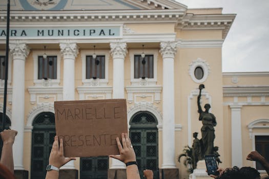 Crowd holding a sign 'MARIELLE PRESENTE' at Rio's city hall.