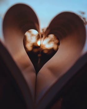 A romantic view of sunset through heart-shaped pages of a book, symbolizing love and literary passion.